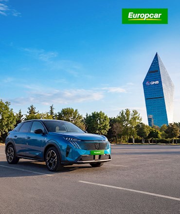 Europcar logosu altında, arkasında QNB kulesinin yer aldığı açık alanda park etmiş mavi Peugeot 3008 otomobil.