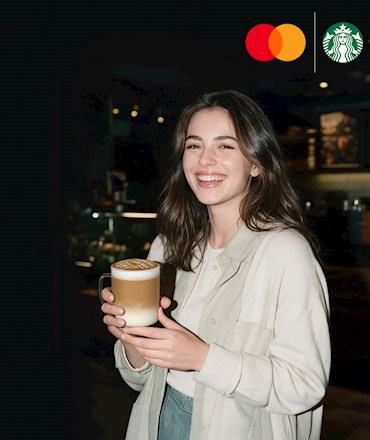 Mastercard ve Starbucks logoları altında, elinde cam kupada katmanlı kahve tutarak gülümseyen genç bir kadın.