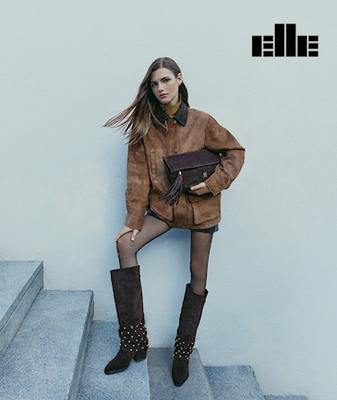 ELLE logosu altında, merdiven basamaklarında süet ceket, zımbalı çizme ve el çantasıyla poz veren kadın modeli.